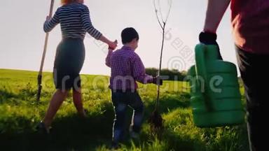 一个友好的家庭要种一棵树。 后视，在前景的<strong>浇水</strong>罐.. 一个<strong>小男孩</strong>在跑